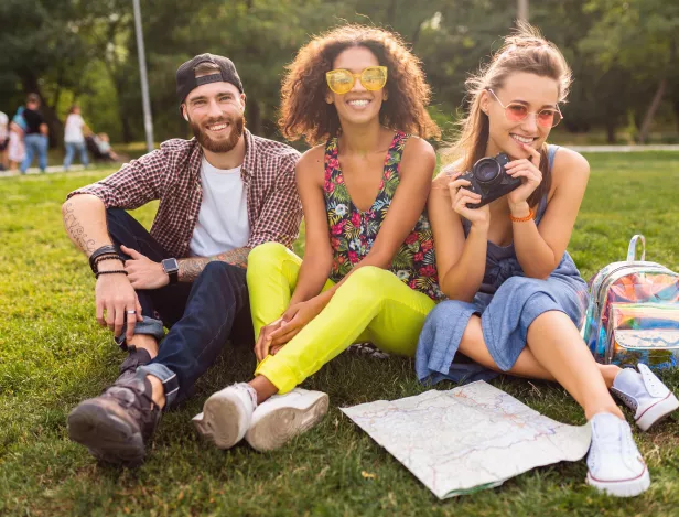 happy-young-company-talking-smiling-friends-sitting-park-man-women-having-fun-together-traveling-with-camera